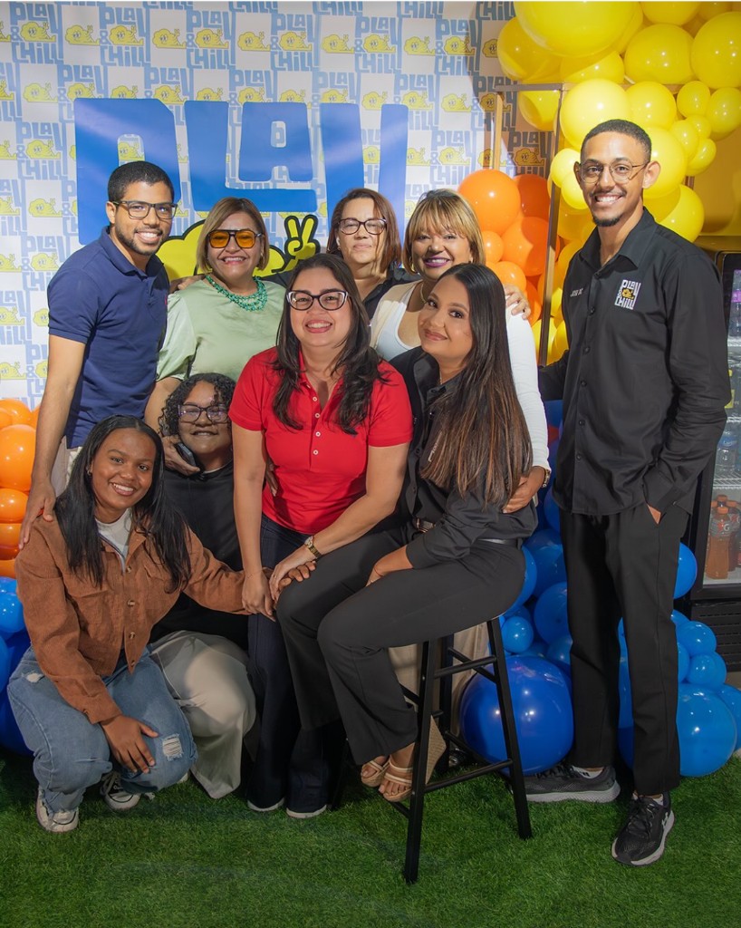 Foto de inauguración Play & Chill: equipo reunido ante el fondo con logo, globos y escenario tipo lounge.